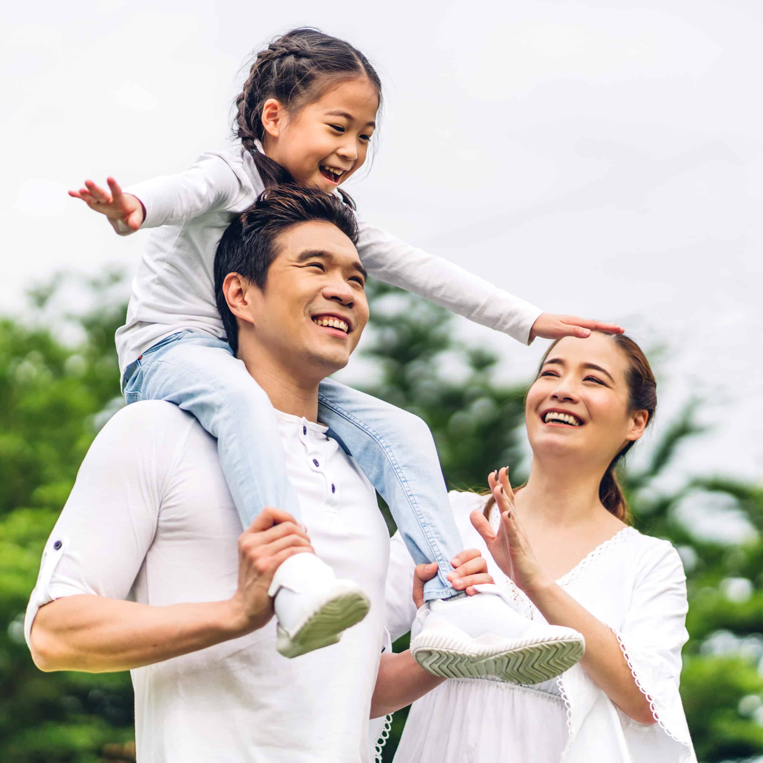 Portrait of enjoy happy love asian family father and mother holding cute little asian girl child smiling playing and having fun moments good time in summer park at home